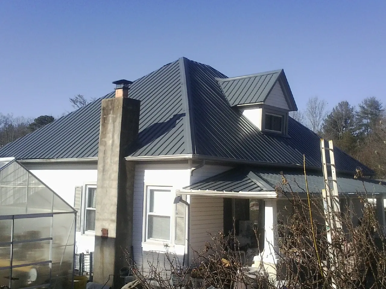 Dark blue standing seam metal roof on a white farmhouse with dormer — Slate & Tile Roof Repair by Roofing Brothers in Declo