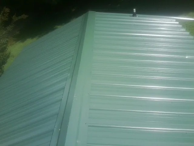 New green metal panels meeting at the ridge of a roof — Flat Roof Repair work by our crew in Declo