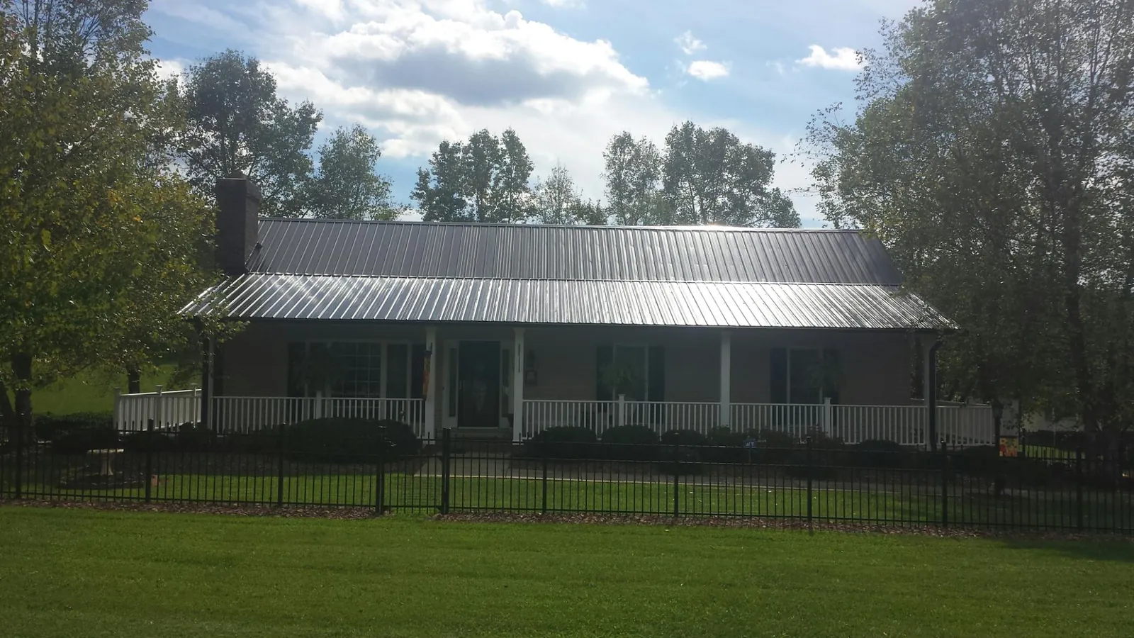 Gray metal roof on a brick ranch with a full width front porch — Gutter Guard Installation work by our crew in Declo